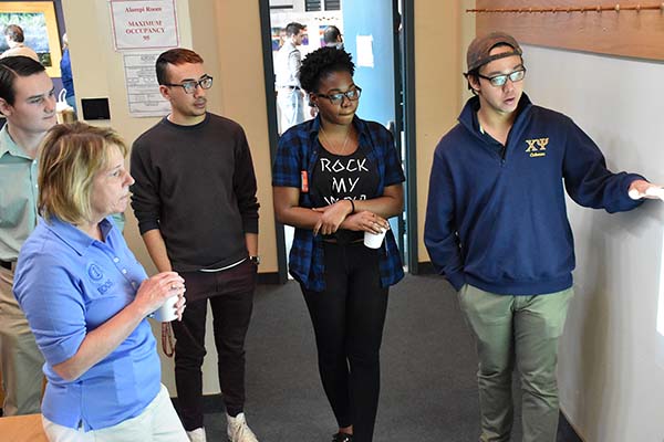 student explains content of white board while other students and Zdenka observe.